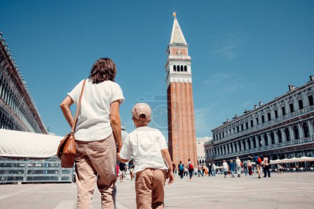 Foto de La pura alegría irradia desde un hermoso niño paseando con su madre por las encantadoras calles de Venecia. Las sonrisas reflejan el esplendor de la ciudad, creando una imagen conmovedora de felicidad, amor y exploración - Imagen libre de derechos