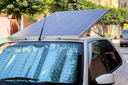 Téléchargez les photos : Voiture compacte garée sur le bord de la route avec panneaux solaires sur le toit - en image libre de droit