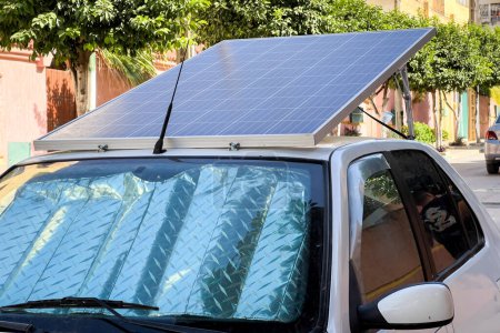 Téléchargez les photos : Voiture compacte garée sur le bord de la route avec panneaux solaires sur le toit - en image libre de droit