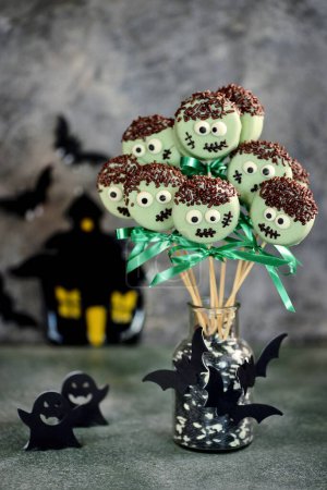 Halloween treat - bright sweet chocolate cakepops monsters on dark background