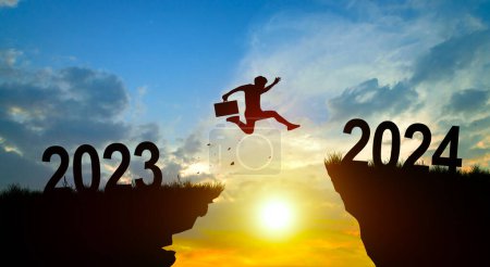 Photo for Welcome merry Christmas and Happy new year in 2024. Man jumping across the gap from 2023 to 2024 cliff with Sunset and Twilight Sky background. - Royalty Free Image