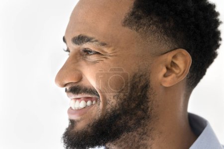 Foto de Vista lateral de cerca retrato de un joven afroamericano feliz mirando hacia adelante, sonriendo, riendo, mostrando dientes blancos sanos. Modelo masculino guapo que promueve el cuidado de la belleza, servicio dental - Imagen libre de derechos