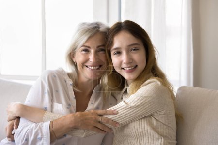 Photo for Portrait of mature mom and pre-teen daughter looking at cam. Familial love, support, understanding between teenager and mother, unwavering affection, genuine friendship, profound sense of connection - Royalty Free Image