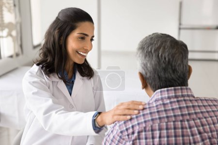 Photo for Happy young doctor woman enjoying medical job, giving support to older patient, talking to man for healthcare examination, checkup, touching shoulder with support, sympathy - Royalty Free Image