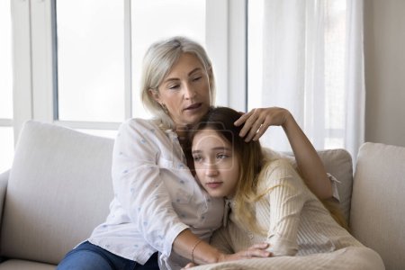Photo for In tender embrace of loving middle-aged mother upset frustrated pre-teen daughter receive wise advice, emotional support, sit together on couch, lead conversation. Understanding, empathy, adolescence - Royalty Free Image