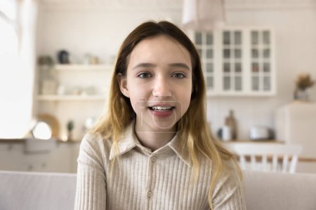 Close up teen girl look at camera, having videocall conversation, talk to friends at online videoconference, enjoy remote communication using modern application, record vlog seated on sofa. Blogging