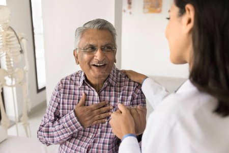 Photo for Young doctor woman calming senior Indian patient, holding mans hand, touching shoulder with comfort, support, compassion, telling good news about health, heart work - Royalty Free Image