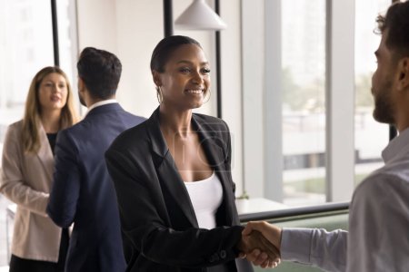 Téléchargez les photos : Happy beautiful African American businesswoman in formal suit shaking hands with company customer, male business partner, smiling, thanking for partnership, closing deal, getting agreement - en image libre de droit