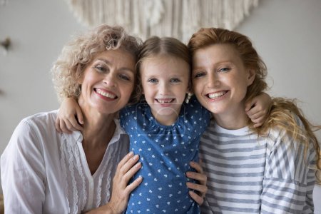 Photo for Portrait of multi-generational women, adorable preschooler 5s girl her young 30s mum and middle-aged 55s granny posing for camera. Motherhood, Happy Mothers Day celebration, family ties and attachment - Royalty Free Image