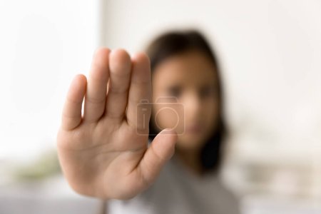 Photo for Scared kid making hand stop gesture, showing palm at camera, symbol of warning, restriction, forbidding, protest. Little girl outstretching arm with open wrist for protection. Close up shot - Royalty Free Image