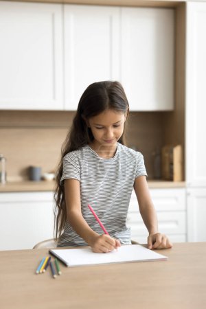 Photo for Positive pretty little kid girl drawing in colored pencils at kitchen table, enjoying creativity, artistic hobby, doing art school homework task, scratching doodles in paper album - Royalty Free Image