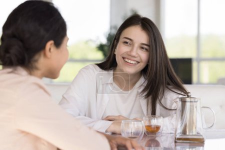 Téléchargez les photos : Heureux divers amis féminins bavarder autour d'une tasse de thé dans un café, se rencontrer pour le petit déjeuner dans un café, parler, rire, profiter de l'amitié, la communication sociale informelle - en image libre de droit