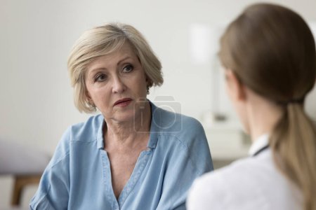 Photo for Serious older patient woman visiting doctor, getting geriatric health problems after medical checkup, listening to practitioner explaining diagnosis, giving treatment, therapy recommendation - Royalty Free Image