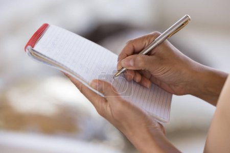 Foto de Mujer escribiendo en papel, usando copybook, bolígrafo, haciendo borrador, accidentalmente planeando tareas. Camarera tomando el orden, escribiendo en cuaderno. Primer plano de las manos femeninas, tiro recortado - Imagen libre de derechos