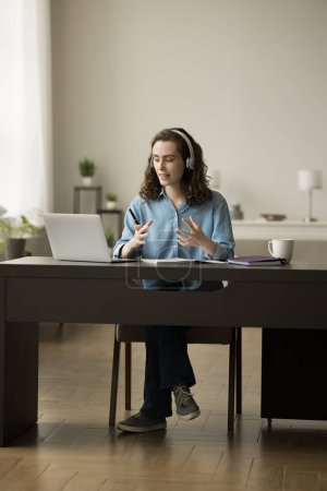Photo for Busy pretty adult student girl talking on video call at laptop, attending online conference, seminar, class, webinar, consulting teacher on Internet, using Internet connection at home office table - Royalty Free Image