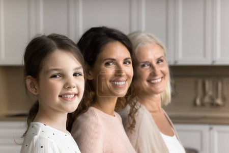 Photo for Happy cute little tween child girl, brunette mom and cheerful grandma posing for family shooting, standing in line, turning faces, heads to camera, smiling. Three female generations portrait - Royalty Free Image