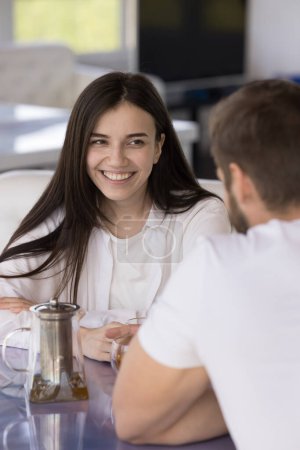 Téléchargez les photos : Belle jeune fille positive parlant au petit ami dans un café, regardant l'homme, souriant, riant. Couple sortir ensemble sur une tasse de thé, réunion pour le petit déjeuner, profiter de la relation amoureuse, loisirs, flirter - en image libre de droit