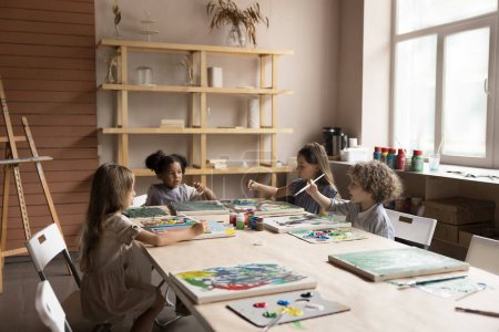 Photo for Class of diverse little pupil kids drawing colorful pictures in creative studio classroom, painting on canvas at table in artistic school, learning art, training creativity, talent - Royalty Free Image