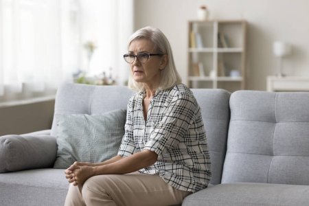 Foto de Sad desperate senior woman suffering from anxious mental disorder, depression, feeling upset, frustrated, nervous about healthcare problems, bad news, crying, sitting on home couch - Imagen libre de derechos