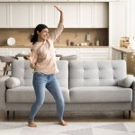 Cheerful energetic young Indian woman dancing at cozy contemporary home, enjoying music, activity, leisure, motion, party, having fun, laughing, singing song, celebrating property buying