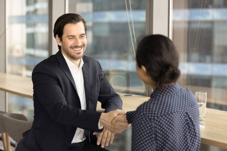 Téléchargez les photos : Positive confident business leader man giving handshake to colleague woman, hiring candidate, new employee, closing contract, deal with partner. Male and female professionals shaking hands - en image libre de droit