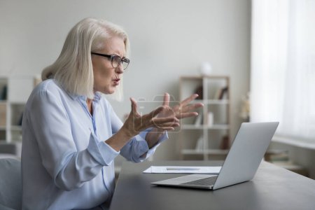 Businesswoman angry because her laptop is broken, swearing, gesturing, technical glitch disrupting her workflow, encountering critical errors, data loss of important project, slow internet connection