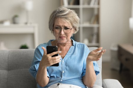 Photo for Annoyed frustrated mature retired woman in glasses getting problems with smartphone, trouble with online connection, communication, reading bad news, using mobile phone - Royalty Free Image