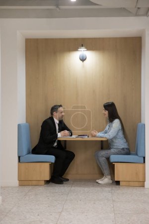 Téléchargez les photos : Divers collègues d'affaires positifs discutant dans une cabine de bureau divisée en collaboration contemporaine, assis à des tables de travail dans de petites cabines séparées, se réunissant pour discuter - en image libre de droit