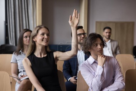 Les gens participent à une conférence ou à un séminaire se réunissent au bureau, une femme souriante attrayante lève la main, pose des questions au formateur d'entreprise. Atelier de bénévolat, de vote ou d'éducation du personnel corporatif