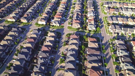 Photo for Aerial view of luxury wealthy style and clean single family homes in America with parking space for cars and large green backyards. Golden Hour evening and houses in very geometrical setting pattern. - Royalty Free Image