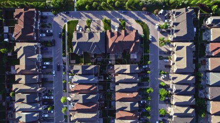 Photo for Aerial footage of Canadian town showing suburban housing estates in geometrical position and rows of houses. Summer golden hour evening with long shadows. - Royalty Free Image