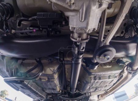 Foto de Auto mechanic view of bottom of the car. Rear differential axle wide angle, rear suspension system and components of exhaust system in passenger city car. All wheel drive system vehicle. - Imagen libre de derechos
