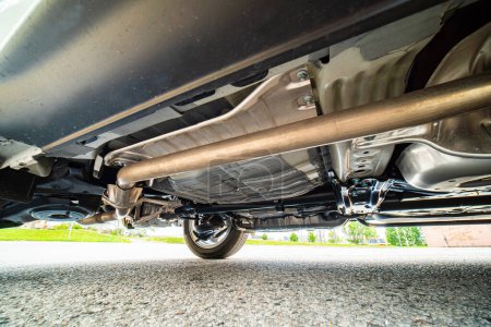 Foto de View of the car by auto mechanic from below. Automobile exhaust system and hoses. All wheel drive trance axle and gas tank with wheels suspension. Garage services, auto repair, road service. - Imagen libre de derechos