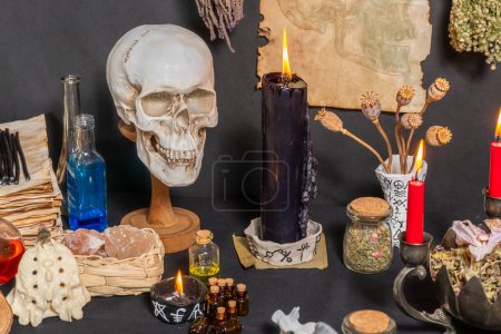 Human skull witchcraft magic ritual. Black magic related objects and tools. Still life in gothic Halloween style of witch alchemist and magician concept. Surrounded by black burning candles.