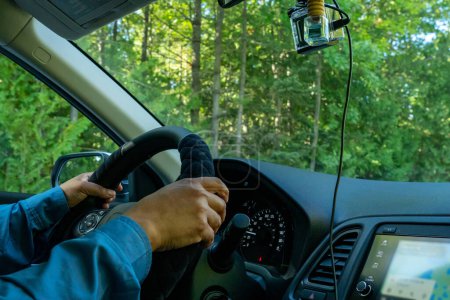 Photo for Woman driver hand on car steering wheels while driving focus on hand. Bumpy rural country side road. Travelling and vacation road trip at sunny summer. Vehicle driver holding car steering wheel. - Royalty Free Image