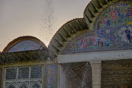 Téléchargez les photos : Shiraz, Iran - 26.06.2023 : Maison Narenjestan Qavam à Shiraz, iran au coucher du soleil. Photo de mise au point sélective de gouttelettes d'eau arrivant à l'étang. - en image libre de droit