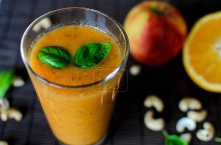 Téléchargez les photos : Smoothie orange cru frais aux pommes, carottes et noix de cajou sur fond sombre - en image libre de droit
