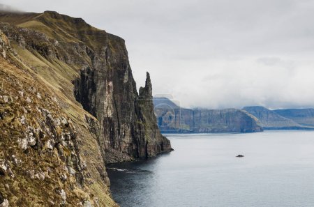 Dramatic cliffs Trollkonufingur, the witches finger, in Faroe Islands, Vagar island, Northern Europe, popular tourist travel destination
