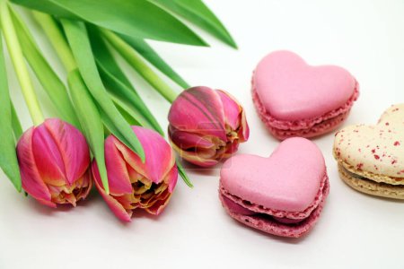 Photo for Bouquet of fresh pink tulips with heart-shaped macroons close-up. - Royalty Free Image