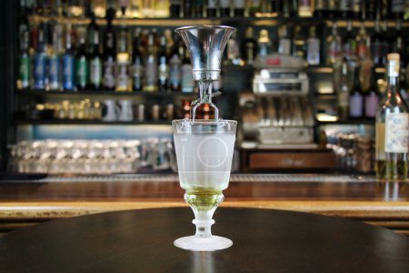 Photo for Classic type of absinthe preparation with brouiller (a tool for preparing absinthe). Glass with absinth on bar counter close-up. - Royalty Free Image