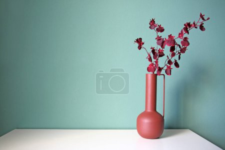 Photo for Blooming branch in a modern ceramic vase on a white table. Space for your text. - Royalty Free Image