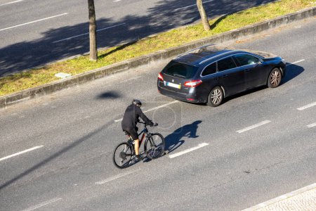 Photo for Lisbon, Portugal, March 12, 2024, Cyclist travels dangerously between traffic on a road with three lanes. - Royalty Free Image