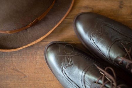 Téléchargez les photos : Fragment de bottes brunes pour hommes brogues aveugles et chapeau melon sur un fond en bois. Vintage hommes style anglais. Vue du haut. - en image libre de droit