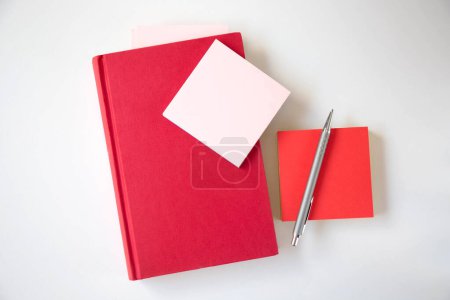 Téléchargez les photos : Un livre rouge et des autocollants pour les notes sont sur la table. Le thème est Journée de l'éducation et de la connaissance. Espace de copie. - en image libre de droit
