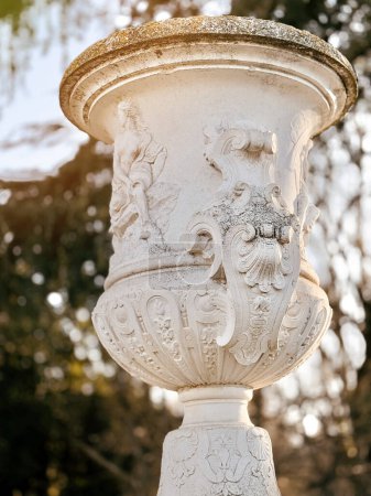 Téléchargez les photos : Un vieux vase de fleurs en pierre avec un bas-relief sur le fond du parc. - en image libre de droit