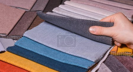 The customer looks at and selects the color fabric she likes, selects the fabric from the fabric swatches for her new sofa.