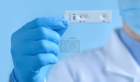 A doctor wearing a protective mask and gloves shows rapid laboratory test for Covid-19 New Variant JN.1 strain to detect IgM and IgG antibodies to the new coronavirus. Negative result