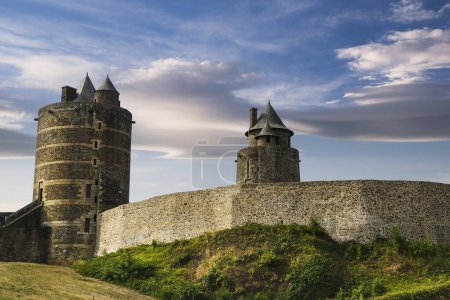 Photo for View of the wall and towers of the medieval castle of the French town of Fougeres built in the 13th century, with a background of blue sky and clouds at sunset. - Royalty Free Image