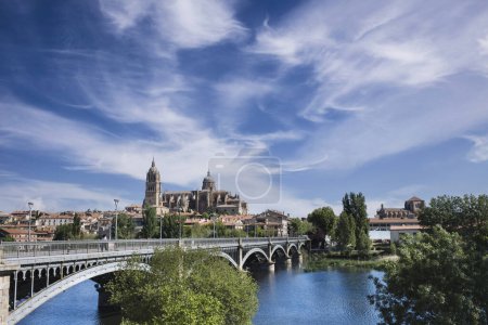 Foto de Perspectiva del puente de Enrique Estevan sobre el río Tormes y la catedral de Salamanca en el fondo con cielo azul y nubes blancas claras. - Imagen libre de derechos