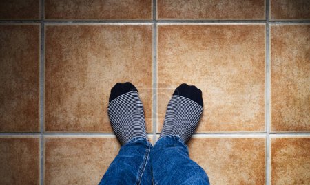 Photo for Image from above of two feet with striped socks on a tiled floor in warm tones. Selfie concept. - Royalty Free Image